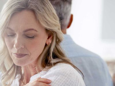 Angebote-Trennung-Frau mittleren Alters schaut mit niedergeschlagenen Augen traurig aus. Sie und ihr Partner haben sich von einander abgewendet.