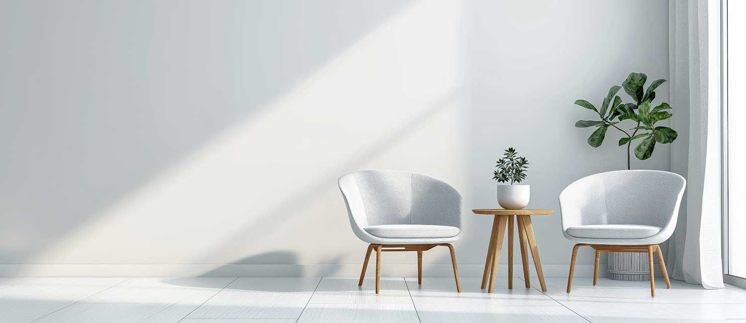 Zwei weiße stühle stehen im Raum, dazwischen ein kleiner Tisch mit einen blumentopf darau. Dahinter eine große grüne Pflaze.