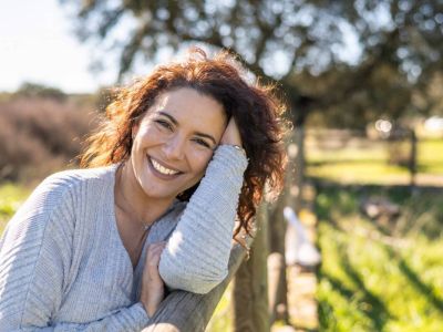 Angebote-Einzelberatung-Junge Frau mit baruenen locken lächelt glücklich unf zufrieden.